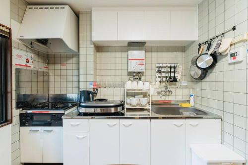 a white kitchen with a sink and a stove at Mont Hotel Higashi mikuni in Osaka