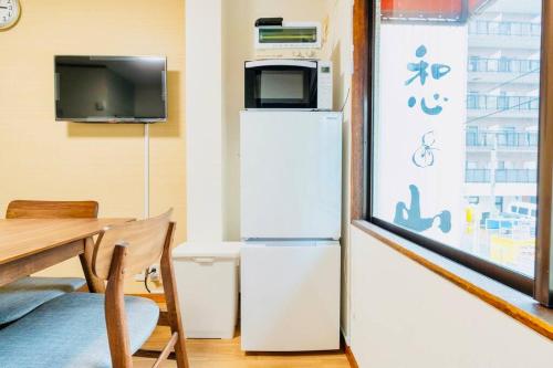 a room with a refrigerator and a tv and a table at Mont Hotel Higashi mikuni in Osaka