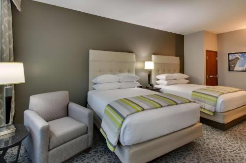 a hotel room with two beds and a chair at Drury Plaza Hotel Dallas Richardson in Richardson