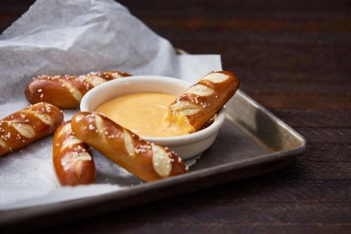 a plate with a bowl of dipping sauce and pretzels at Drury Plaza Hotel Dallas Richardson in Richardson