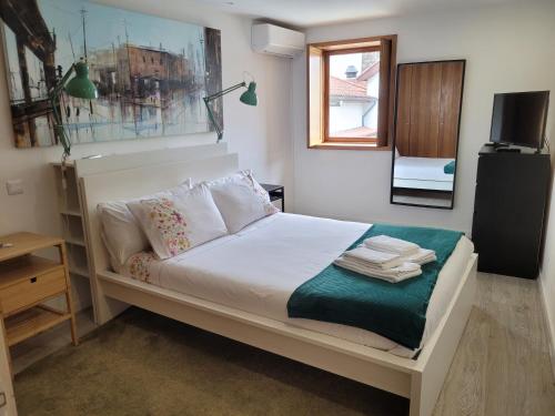 a bedroom with a bed with white sheets and pillows at Apartamento familiar no centro histórico - Afonso Henriques in Braga