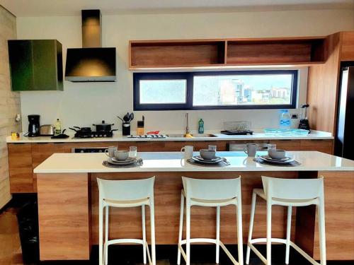 a kitchen with a counter with three stools at Elegante depa cerca de los arcos con amenidades in Hércules