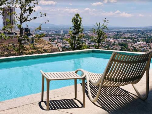 a wooden chair sitting next to a swimming pool at Elegante depa cerca de los arcos con amenidades in Hércules