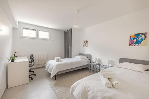 Cette chambre blanche comprend deux lits et une table. dans l'établissement Maison paisible T3 à 20min de Paris, à Vitry-sur-Seine
