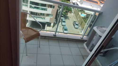 a balcony with a chair and a view of a building at Studio pé na areia, vista, internet e ar in Macaé