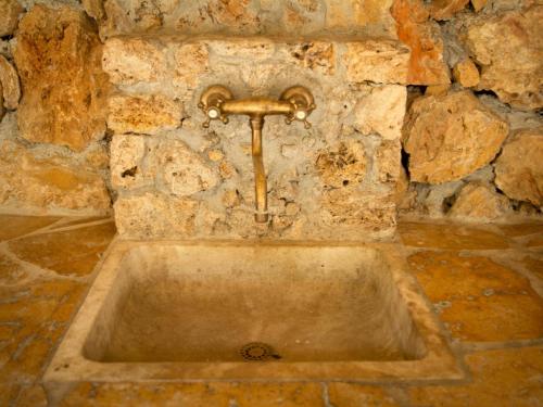 Un fregadero en una pared de piedra con un grifo en Maison Jaune, en Cotignac
