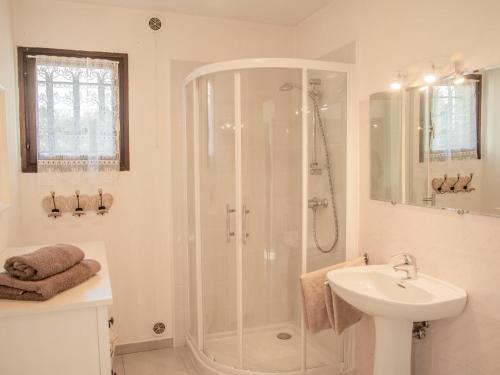 a white bathroom with a shower and a sink at Villa Muguet in Bagnols-en-Forêt