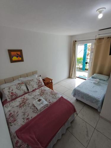 a white bedroom with a bed and a window at Pousada Recanto das Oliveiras-Búzios in Búzios