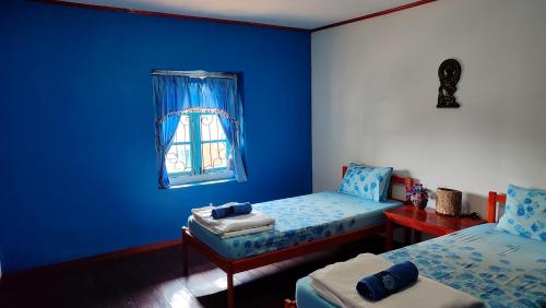 a blue room with two beds and a window at MJR Ticketing Guest House in Ruteng