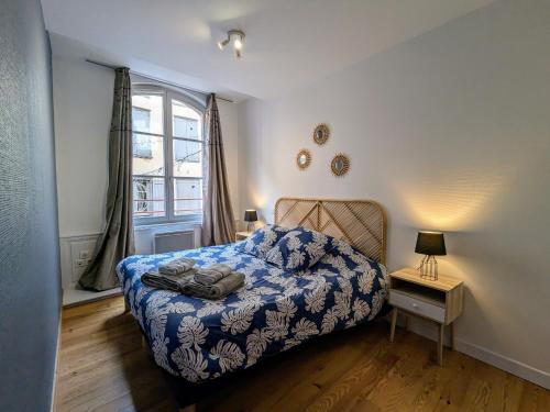 une chambre avec un lit avec une couverture bleue et une fenêtre dans l'établissement Charmant 2 pièces au pied de la cathédrale, lumineux et tout inclus, idéalement situé en centre-ville. - FR-1-582-379, au Puy-en-Velay