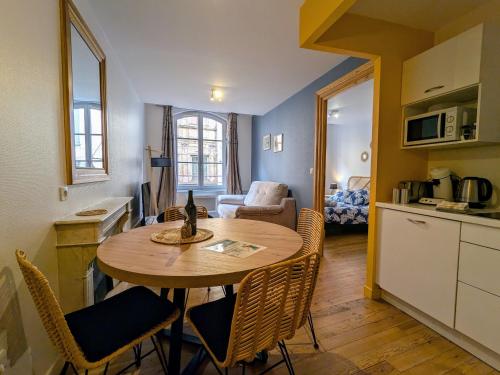 une cuisine et un salon avec une table et des chaises dans l'établissement Charmant 2 pièces au pied de la cathédrale, lumineux et tout inclus, idéalement situé en centre-ville. - FR-1-582-379, au Puy-en-Velay