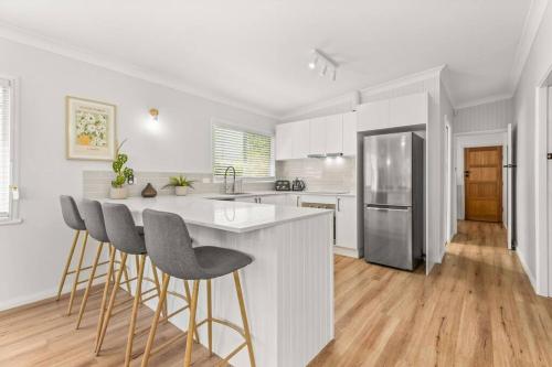 a white kitchen with a counter and stools at SeaSalt72 in Erowal Bay