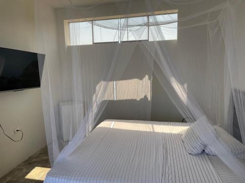 ein Schlafzimmer mit einem weißen Bett mit einem Fenster in der Unterkunft Don Amado in La Bocana