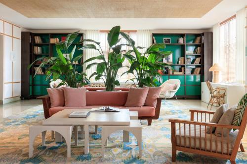 a living room with a pink couch and plants at Kimpton Surfcomber Hotel by IHG in Miami Beach