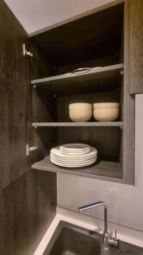 a kitchen with a sink and plates in a cabinet at Loxwood House by Cozy in Accra