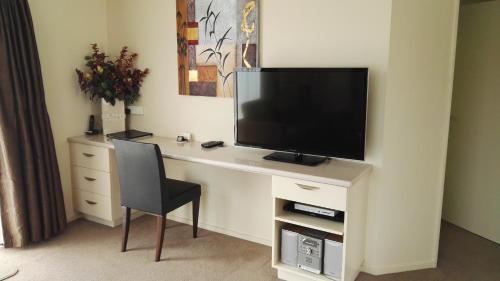 a room with a desk with a tv and a chair at Cedar Grove Motor Lodge in Nelson