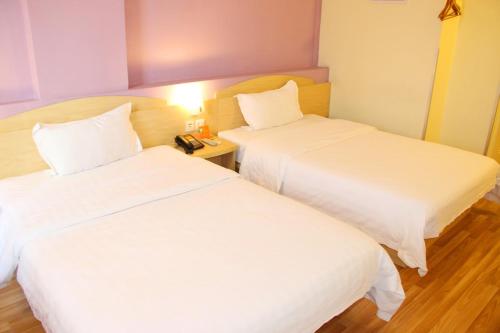 two beds in a hotel room with white sheets at 7Days Inn Duyun Bus Terminal Station in Duyun