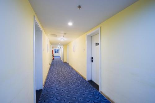 a hallway of an office with white walls and blue carpet at 7Days Inn Shizheng Square in Tai'an