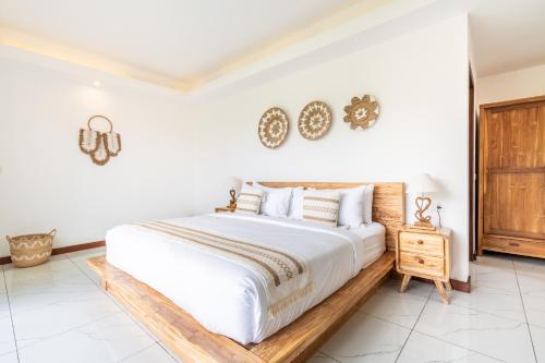 a bedroom with a large white bed and a wooden nightstand at Akasia Hill Villas in Nusa Dua
