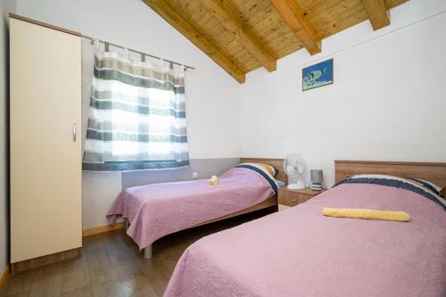 two beds in a room with pink sheets at Secluded fisherman's cottage Cove Dragnjevica - Telascica, Dugi otok - 19966 in Sali
