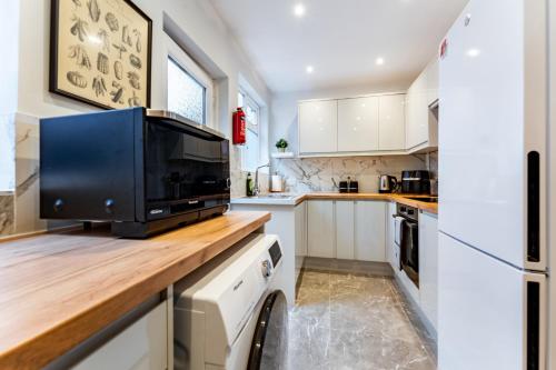 a kitchen with white cabinets and a television on a counter at Greenview double bedroom 5 in Oxford