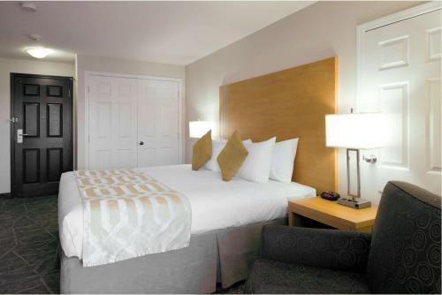 a hotel room with a large bed and a chair at Coast Osoyoos Beach Hotel in Osoyoos