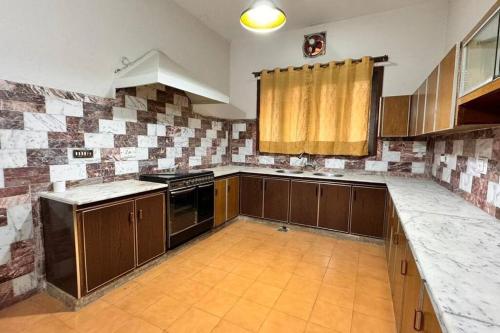 a kitchen with wooden cabinets and a stove top oven at Spacious 4-Bedroom Luxury Stay in the Heart of F10 in Islamabad