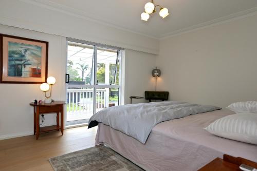 a white bedroom with a large bed and a window at Holiday house in totara park in Auckland