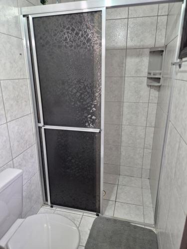 a shower with a glass door in a bathroom at Kitnet Balneário Flamingo in Matinhos