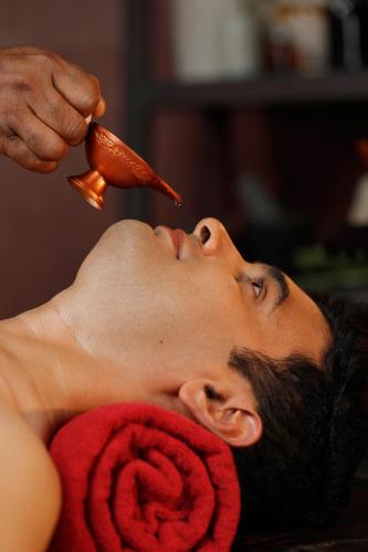 a man getting his hair cut with a hot dog at Namasthe Ayurveda and Yoga Retreat Cochin in Nedumbassery