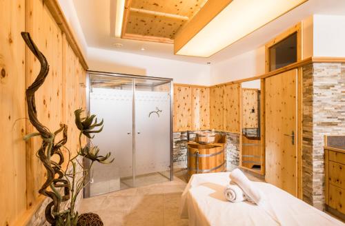 a bathroom with wooden walls and a glass shower stall at Hirschen Wohlfühlhotel in Schoppernau