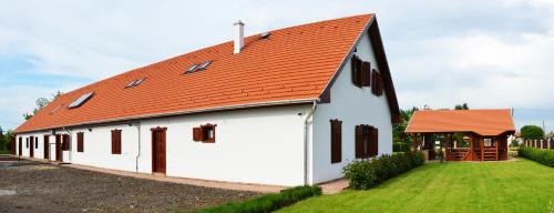 ein weißes Gebäude mit orangefarbenem Dach in der Unterkunft Falusi Patika - Tisza-tó Vendégház in Tiszaszőlős