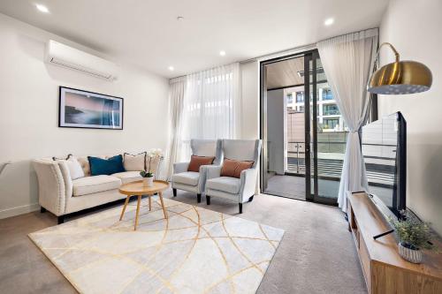 a living room with a couch and chairs and a tv at Waterfront luxury living - Wynyard Quarter in Auckland