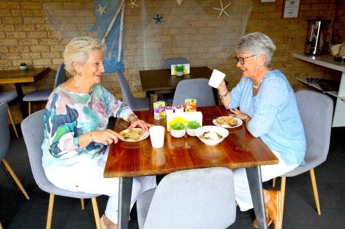 Dos mujeres mayores sentadas en una mesa comiendo comida en Tweed Harbour Motor Inn, en Tweed Heads