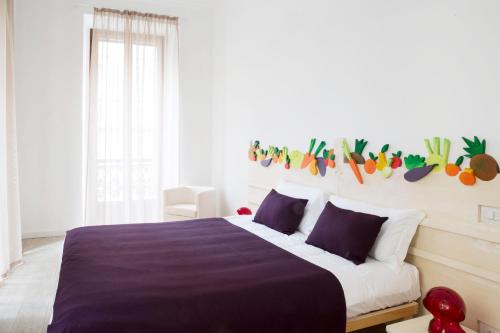 a white bedroom with a large bed with purple sheets at TorinoToStay Apartments in Turin