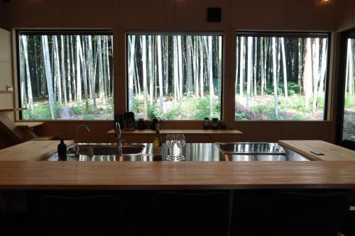 a kitchen with a wooden counter top and two windows at and FOREST勝浦 竹の離れ 美しい竹林に囲まれ露天風呂とSAUNAを楽しむ大人の離れ 天然鉱泉 BBQ ペット 最大8名 勝浦 in Katsuura