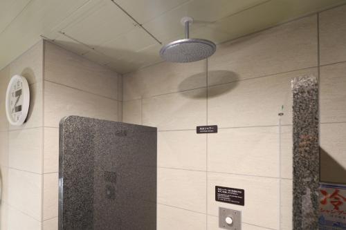 a bathroom with a shower and a clock on the wall at global cabin Yokohama Chinatown in Yokohama