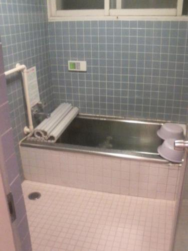 a blue tiled bathroom with a sink and a toilet at ペンションローザンヌ in Fujikawaguchiko
