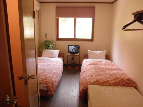 two beds in a room with a window at ペンションローザンヌ in Fujikawaguchiko