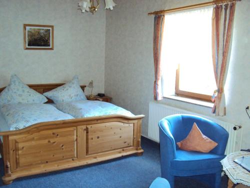una camera con un letto, una sedia blu e una finestra di Ferienwohnungen Hasenpatt a Bad Sachsa