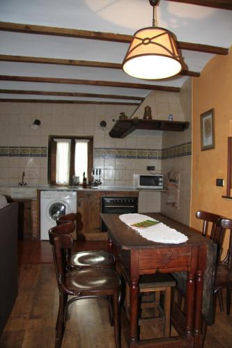 a kitchen with a wooden table and chairs and aendant light at Ca María Fayas in Proaza