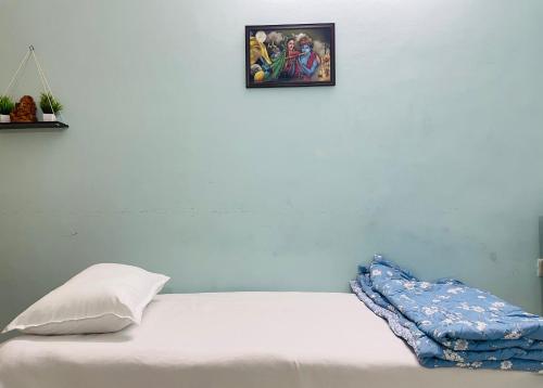 a white bed with a pillow and a picture on the wall at Best Homestay in Puttaparthi