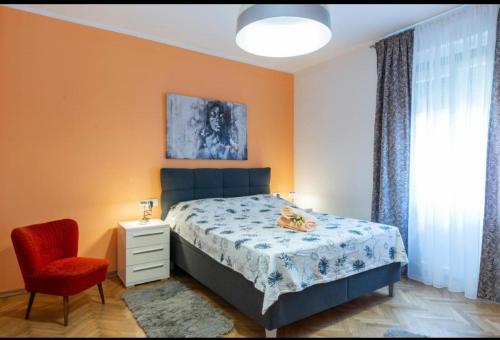 een slaapkamer met een bed en een rode stoel bij Apartment Punta with garage, balcony, garden and sea view in Opatija