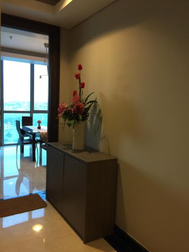 a living room with a vase of flowers on a cabinet at Signature Apartment @ The Windsor in Jakarta