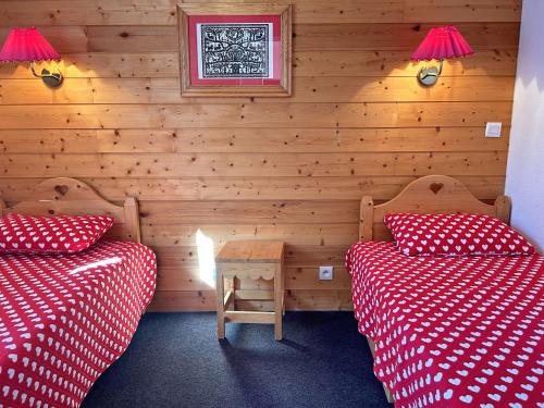 Cette chambre comprend 2 lits avec des draps rouges et blancs. dans l'établissement Appartement ski avec piscine, sauna et WiFi - FR-1-330-585, à Risoul