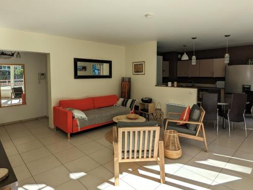 un salon avec un canapé rouge et une cuisine dans l'établissement T3 76m² avec terrasse, balcon, à 100m de la plage d'Eyrac, parking et WIFI - FR-1-420-154, à Arcachon