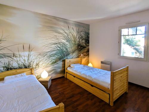 deux lits dans une chambre avec un tableau au mur dans l'établissement T3 76m² avec terrasse, balcon, à 100m de la plage d'Eyrac, parking et WIFI - FR-1-420-154, à Arcachon
