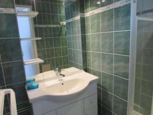 une salle de bain carrelée verte avec un lavabo et un miroir dans l'établissement Maisonnette avec piscine et animaux admis proche plage à Erdeven - FR-1-479-170, à Erdeven