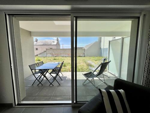 une porte en verre avec une table et des chaises sur un balcon dans l'établissement Étel - Appt. moderne 2 pièces, Wifi & parking, à 700m de la plage - FR-1-479-171, à Étel