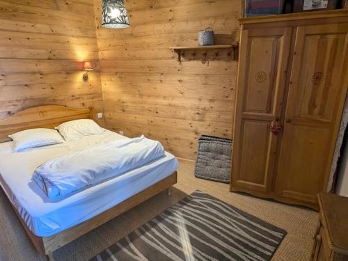 une chambre avec un lit et un mur en bois dans l'établissement 3 Pièces au pied des pistes, 7 pers, balcon, cuisine équipée - FR-1-557-137, à Les Adrets